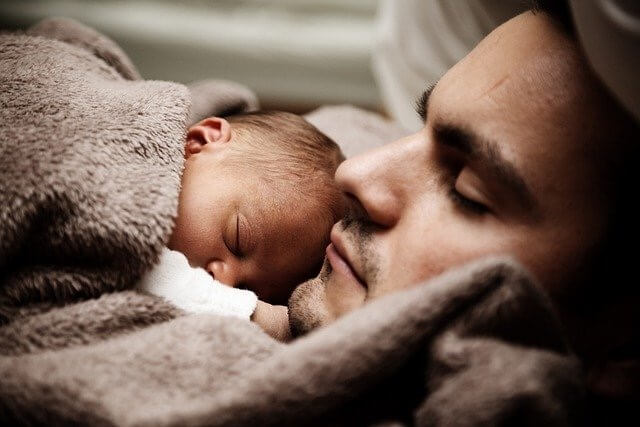 Baby liegt auf dem Bauch vom Vater ganz nah am Gesicht